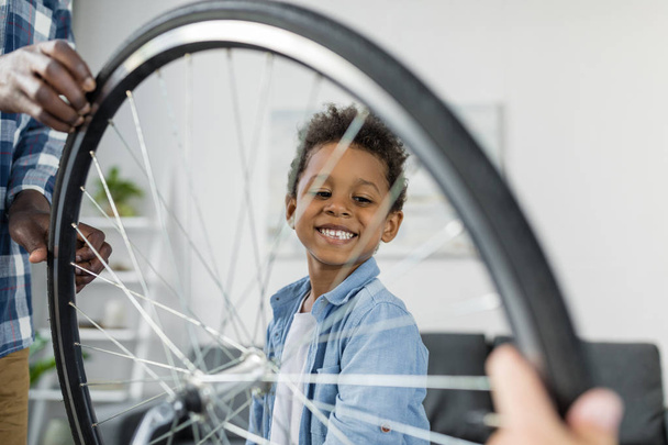 Glücklicher afrikanischer Junge repariert Fahrrad - Foto, Bild
