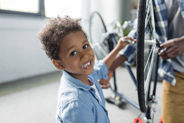 adorable afro boy repairing bicycle - Valokuva, kuva