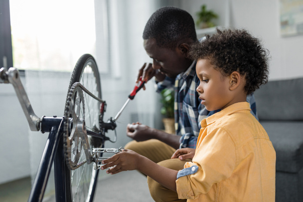afro father and son repairing bicycle - Foto, Bild