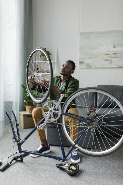afro man repairing bicycle at home - Valokuva, kuva