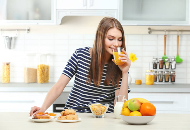 Young beautiful woman having breakfast at kitchen - Фото, зображення