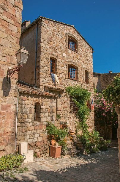 Close-up of stone house facade with bindweed in an alley, at Les Arcs-sur-Argens. - Foto, afbeelding