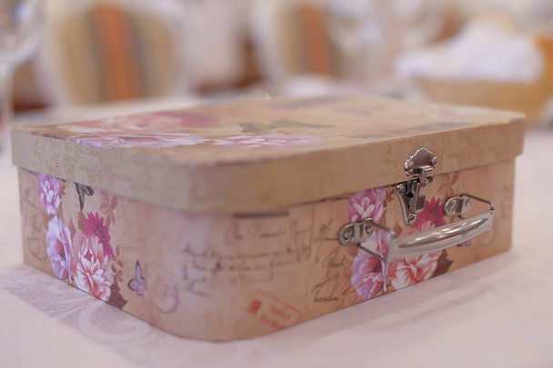 Οριζόντια βολή της περίπλοκα στρογγυλεμένη γωνία κουτί, ένα τυπικό χρήματα, δώρα και μνήμες συγκέντρωσης σε γαμήλια τελετή. Vintage κουτί σε παστέλ χρώματα με floral τυπωμένη ύλη.  - Φωτογραφία, εικόνα