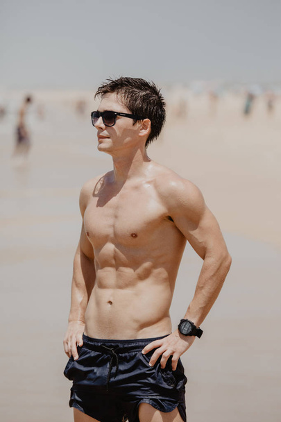 Handsome young muscular male model on the beach enjoying summer - Fotó, kép