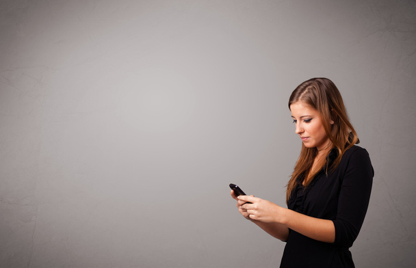 young lady standing and holding a phone with copy space - Foto, imagen