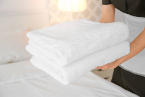Maid holding stack of towels - 写真・画像