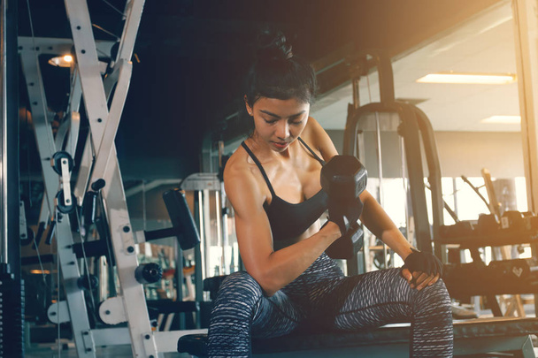 Asian woman's arm holding dumbbell and pull up with strong abs a - Photo, Image