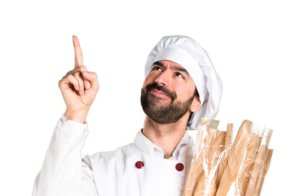 Junge Bäckerin hält Brot in der Hand und zeigt nach oben - Foto, Bild