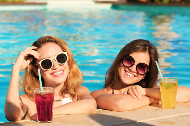 Two women with cocktails in pool - Foto, afbeelding