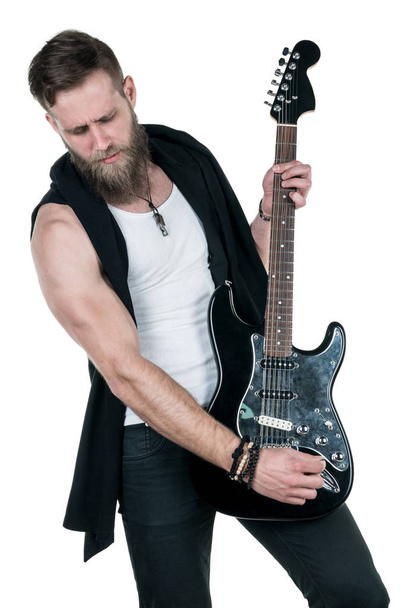 KIEV, UKRAINE - May 03, 2017. Charismatic and stylish man with a beard playing an electric guitar on a white isolated background. Vertical frame - Photo, image