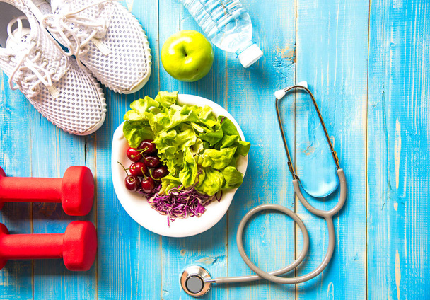 Healthy lifestyle sport equipment fitness, sneakers, green apple, fresh water and healthy food on blue wood background.  Healthy Concept. - Photo, Image