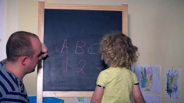 Man and little girl child learning numbers and letters on chalk black board - Metraje, vídeo