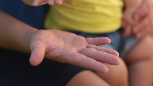 Otec drží ruku nezletilého syna v jeho dlani - Záběry, video
