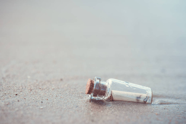 Bericht in de fles weggespoeld uit de zee tegen de ondergaande zon naar beneden - Foto, afbeelding
