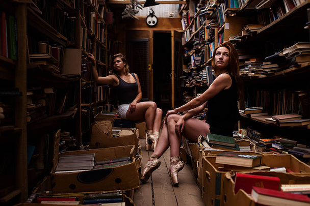 Portrait of two ballerina girsl in vintage book store wearing casual clothes - Foto, Imagen