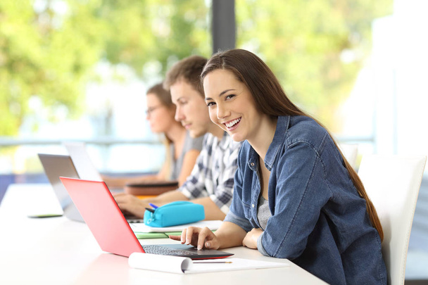 Student with laptop posing in a classroom - Zdjęcie, obraz