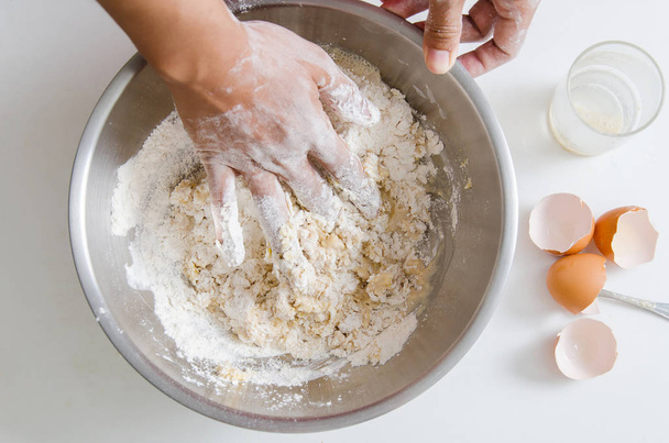 Mezcla a mano levadura, yema de huevo, azúcar y harina en un tazón
 - Foto, imagen