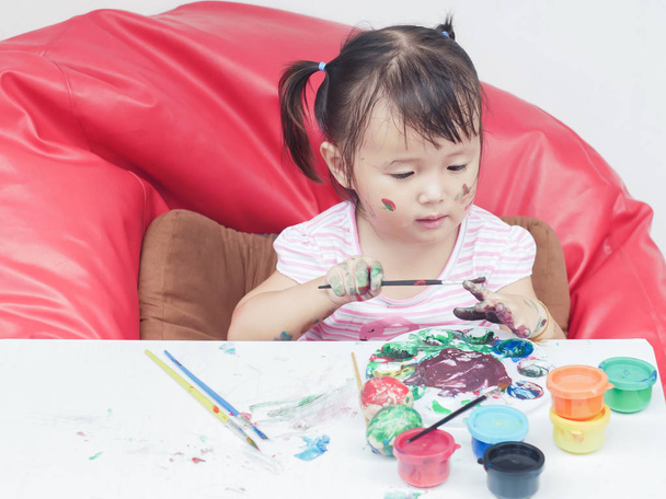 Little Girl Painting with paintbrush and colorful paints children development concept - Foto, imagen