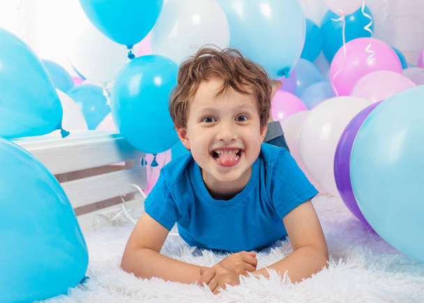 Hilarious funny baby boy with bunch of colorful balloons. Shows language. Isolated on white. - Fotografie, Obrázek