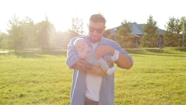 A man is holding his son in his arms outdoors - Footage, Video