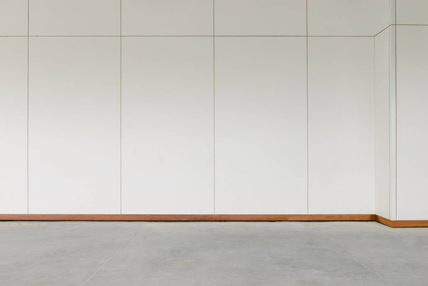 Sala vazia com piso de concreto e parede laminada de madeira branca
 - Foto, Imagem