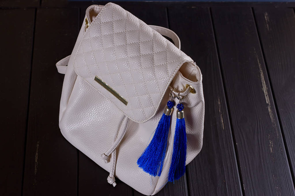 mochila pequena mulher de couro branco e brincos azuis de linha
 - Foto, Imagem