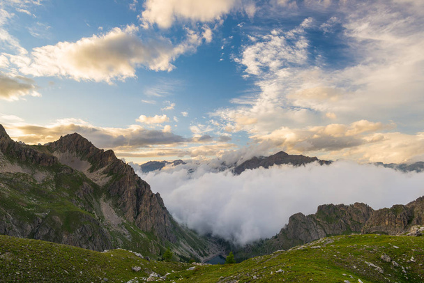 Última luz solar cálida en el valle alpino con picos de montaña brillantes y nubes escénicas. Alpes franceses italianos, destino de viaje de verano
. - Foto, Imagen