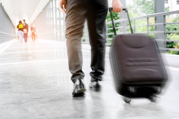 Businessman holding trolley bag going up on travel - Фото, изображение