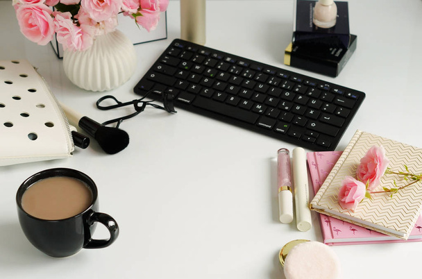 Female make up accessories, cup of cofee and bouquet of pink roses on white background. Flat lay, top view feminine desk, workspace with laptop.  - Фото, зображення