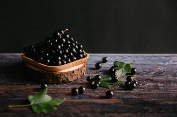 коричневая тарелка со спелой черной смородиной
  - Фото, изображение