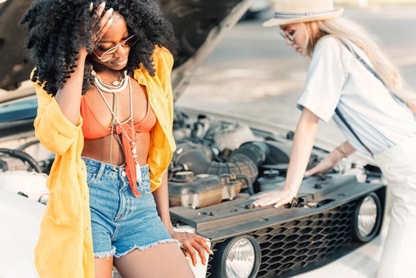 femmes multiethniques debout près de voiture cassée
 - Photo, image