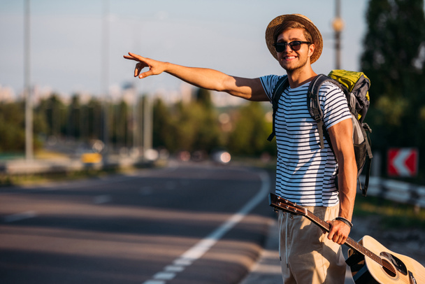 młody człowiek z gitara hitchhiking sam - Zdjęcie, obraz