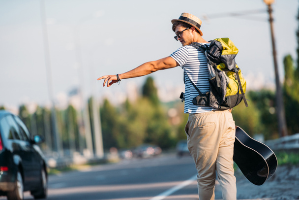 young man with guitar hitchhiking alone - Valokuva, kuva