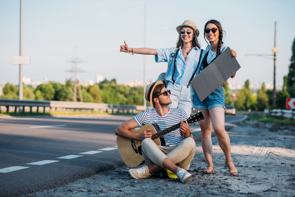 multicultural friends hitchhiking together - Фото, изображение