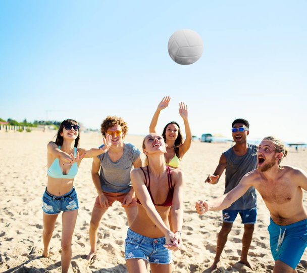 Groep vrienden spelen op beachvolleybal op het strand - Foto, afbeelding