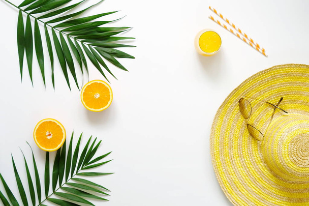 Summer or travel concept.Palm branches, hat, sunglasses and orange juice on white background. Flat lay, top view.Copy space - Φωτογραφία, εικόνα