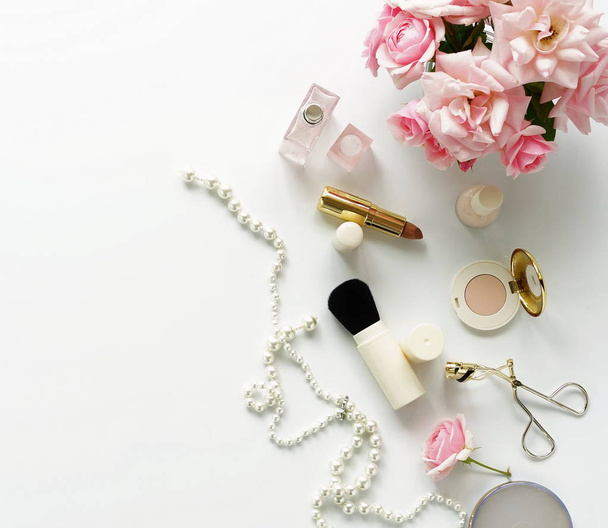 Flat lay, top view feminine desk, female make up accessories and bouquet roses.Beauty blog concept.Copy space - Foto, imagen