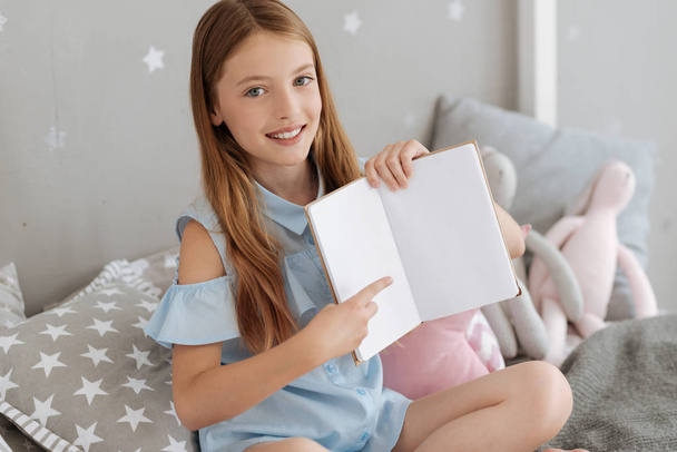 Adorable girl pointing toward page in notebook - Fotó, kép