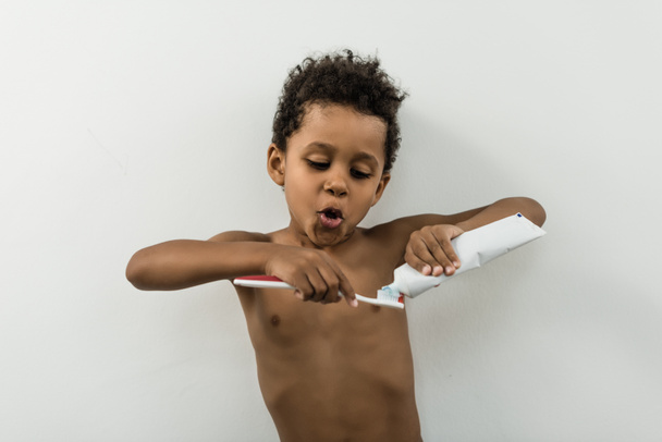 niño aplicando pasta dental en el cepillo
 - Foto, Imagen
