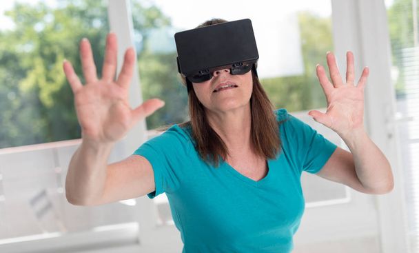 Женщина с помощью гарнитуры виртуальной реальности
 - Фото, изображение