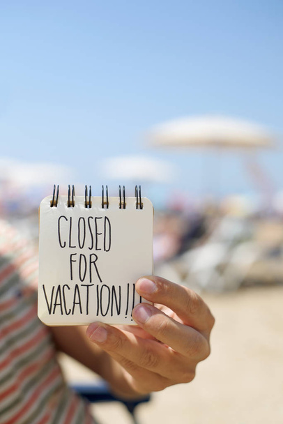 man with a note with the text closed for vacation - Photo, Image