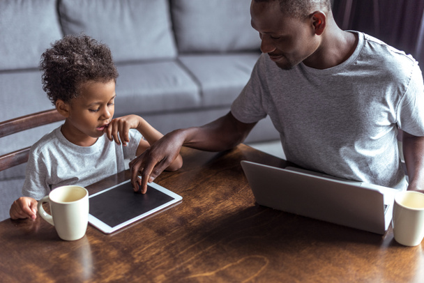 vader en zoon met laptop en tablet - Foto, afbeelding