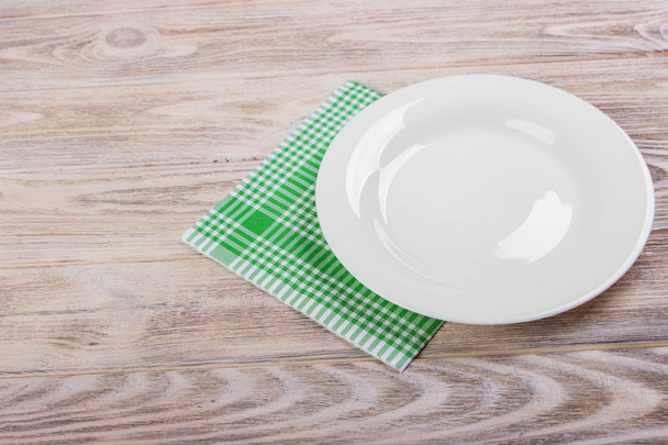 Empty plate and towel over wooden table background. View from above with copy space - Photo, Image