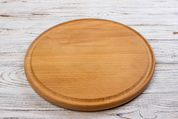 Wooden round empty board for pizza on wood table background, top view. Mockup for menu, recipe or any dish. Vertical image - Photo, Image