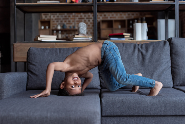 niño sin camisa jugando en el sofá
 - Foto, Imagen