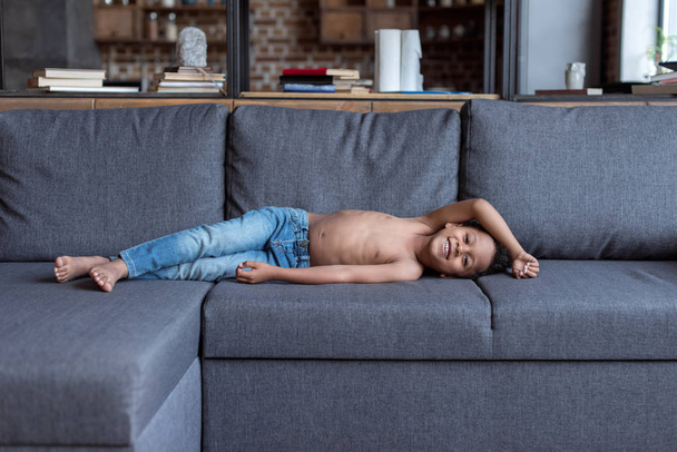 niño sin camisa jugando en el sofá
 - Foto, Imagen