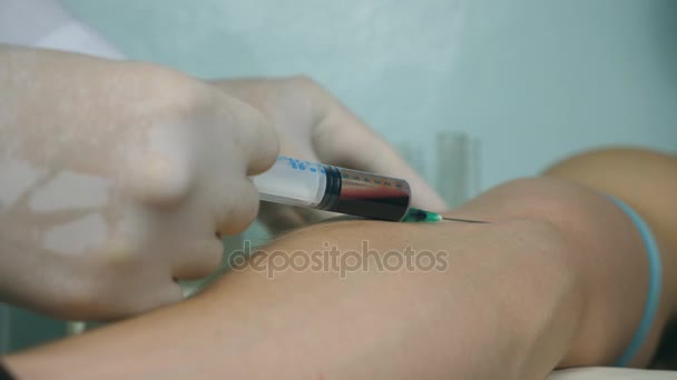 Hand of doctor extracts a syringe from a vein of patient. Takes a blood sample for tests. Arm of medic taking blood. Close up - Video