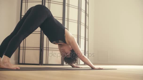 A young woman performing yoga-asanas in the hall. - Кадри, відео