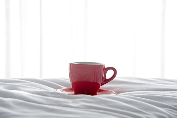 Fresh morning coffee in red cup on the bed - Φωτογραφία, εικόνα
