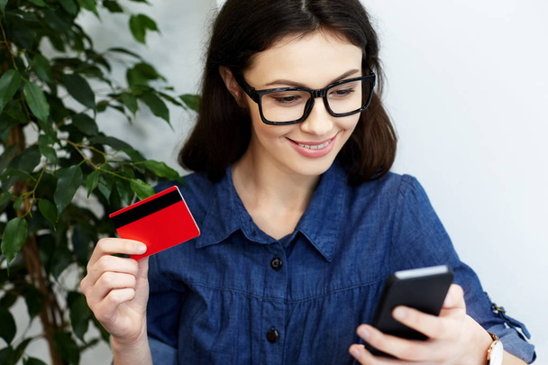 жінка тримає кредитну картку і телефон
 - Фото, зображення